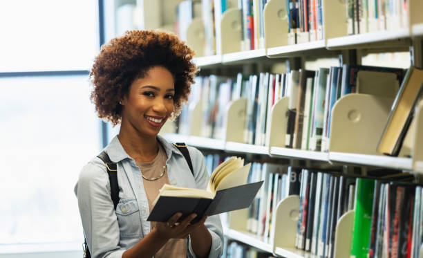 istock Young African-American woman in library looking for book 1617244410