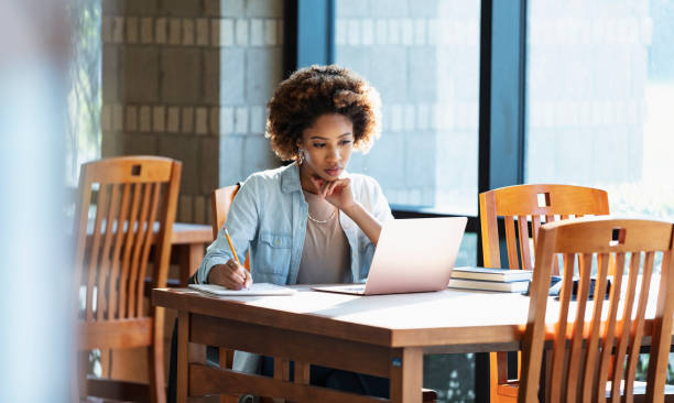 istock Young African-American woman using laptop at table 1617244429