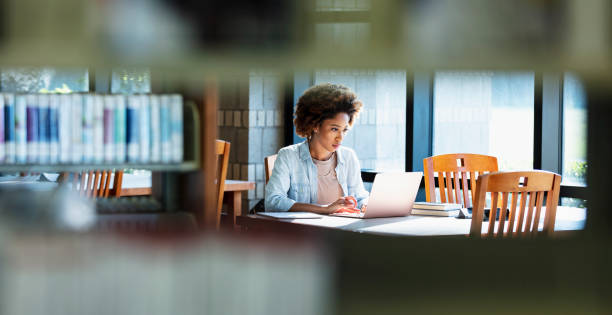 istock Young African-American woman using laptop at table 1617244500