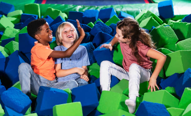 Three multiracial children play in pool of foam blocks