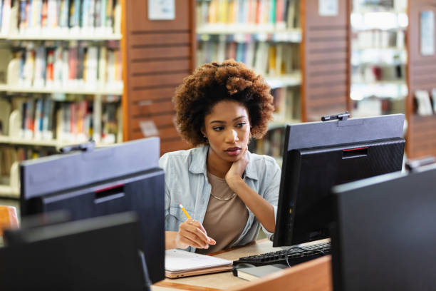 istock Young African-American woman using computer in library 1617244520