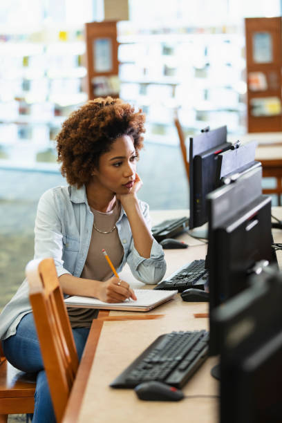 istock Young African-American woman using computer in library 1617244539