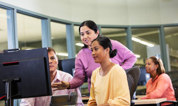 Adult Student Using Computer 80+ Instructor Helping Diverse Group Of Mature Adults In Computer Lab ...