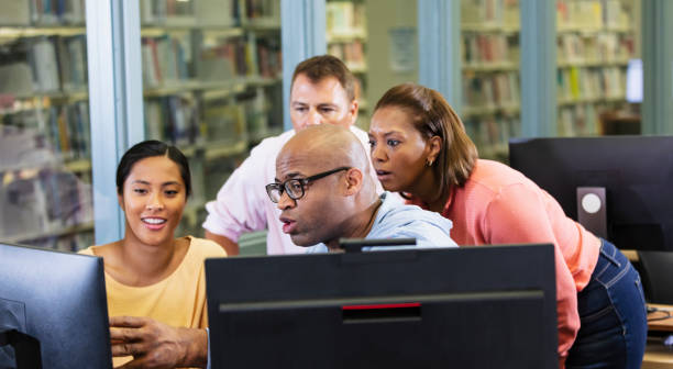 istock Group of adults gathered around desktop computer screen 1617247859