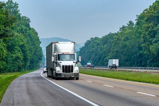 Horizontal shot of a white eighteen wheeler on an interstate with room to crop.