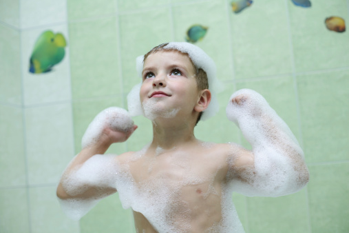 The boy takes a shower in the bathroom, with a cheerful mood