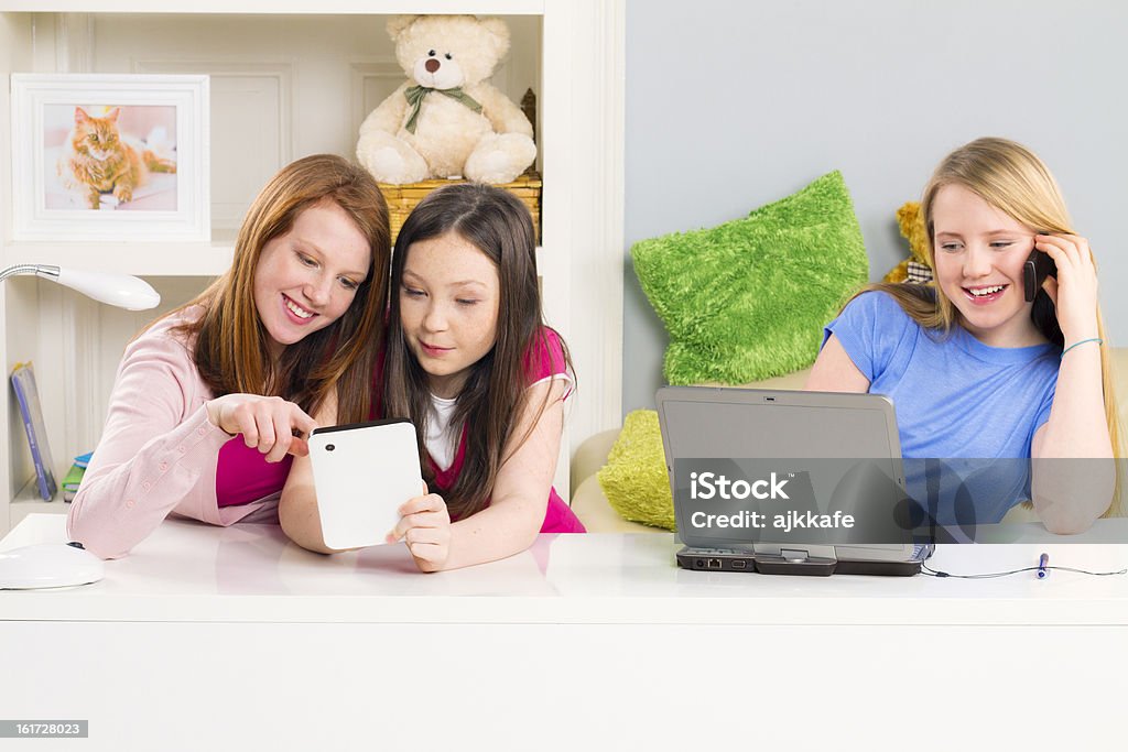 Girls with digital accessories Teenage girls sitting at the table, using digital accessories and having fun 10-11 Years Stock Photo