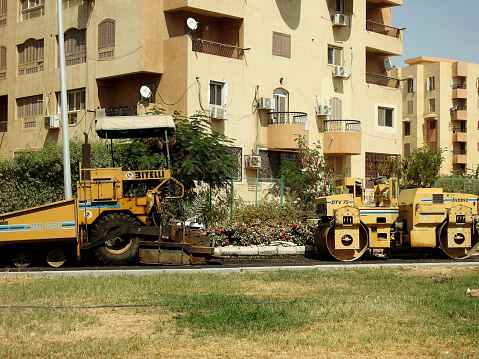 Cairo, Egypt, July 21 2023: Asphalt paver trucks and compactors, A paver (road paver finisher, asphalt finisher, road paving machine) is a piece of construction equipment used to lay asphalt concrete, selective focus