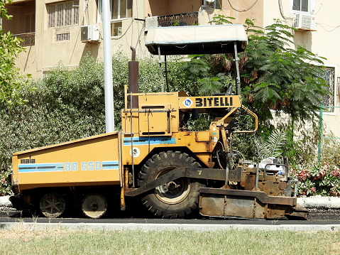 Cairo, Egypt, July 21 2023: wheeled asphalt paver truck, A paver (road paver finisher, asphalt finisher, road paving machine) is a piece of construction equipment used to lay asphalt concrete, selective focus