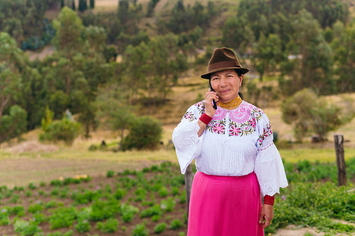 Indigenous woman talking on the phone in the field
