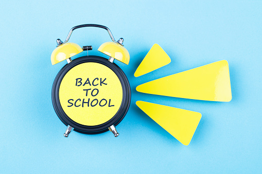 Alarm clock and papers on blue background