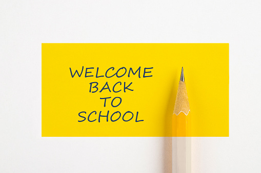 Yellow pencil with yellow rectangle and text Welcome back to school isolated on white background