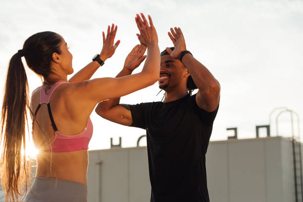 istock Man and woman doing a high five during a workout routine on the roof 1617386000