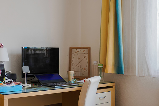 Messy work desk with laptop and equipments. Home office workspace.