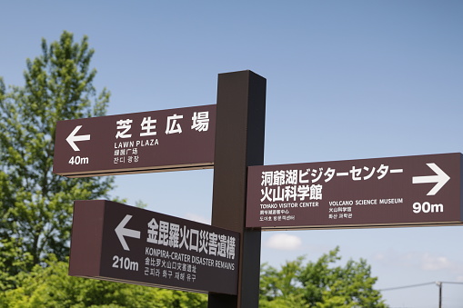 Toyako-cho, Japan - June 8, 2023: Multilingual directional signs point to different sites in the active volcanic landscape in the Mount Usu and Lake Toya area.