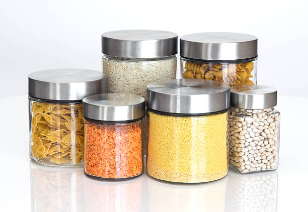 Dry food ingredients in varying sized glass jars on white stock photo