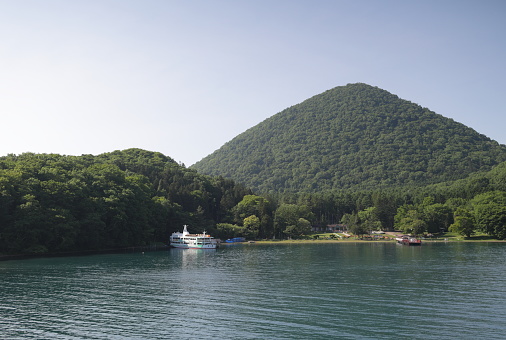 Toyako-cho, Japan - June 8, 2023: A tour boat docks at Oshima Island in Lake Toya, a caldera lake. Spring afternoon in the volcanic landscape of Shikotsu-Toya National Park.