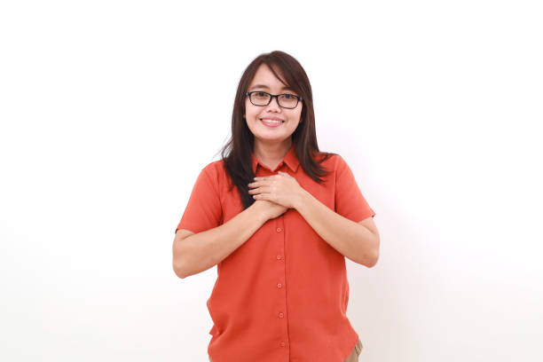 istock Relieved young asian woman standing while holding her chest. Isolated on white 1617447332