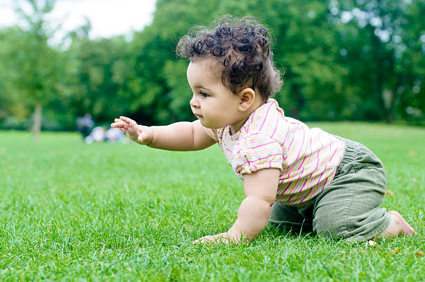 Royalty free stock photo of an 8 months old girl crawling on grass.