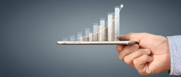istock Hand holding smartphone device and touching screen. Stock exchange market concept. looking 1617532833