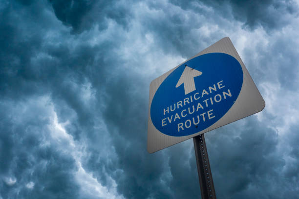 Composite image of a hurricane evacuation route sign against a stormy sky.