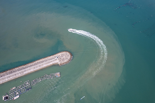 Aerial view of a ship sailing away from the fishing port dam
