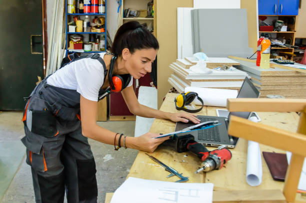 istock A Carpenter Woman is Looking at the Laptop in Workshop and Working on New Projects. 1617560795