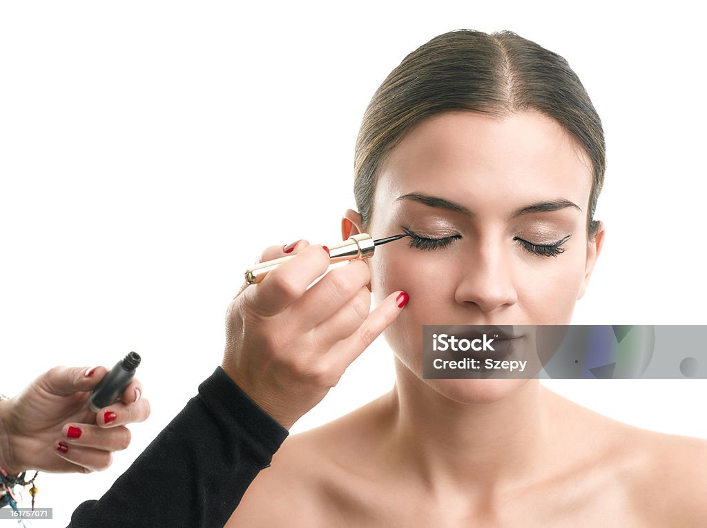 Makeup artist applying eyeliner on eyelid Makeup artist applying eyeliner on eyelid. Isolated on white background. Adult Stock Photo