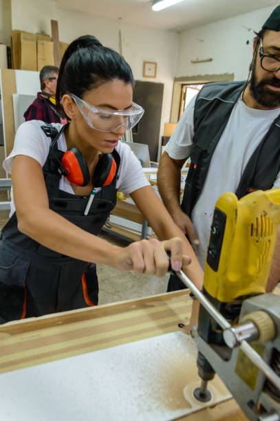 istock A Young Female Carpentry Worker is Working on Woodworks Using a Large Electric Drill with the Help of Coworker. 1617573752