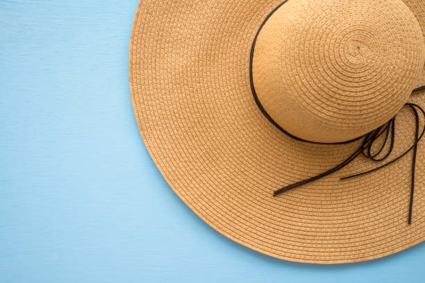 istock Large brown lady summer hat on blue wooden background. 1617574392