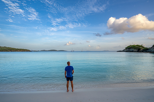 Man Enjoying a Vibrant sunrise over famous Trunk Bay on the tropical Caribbean island of St. John in the US Virgin Islands