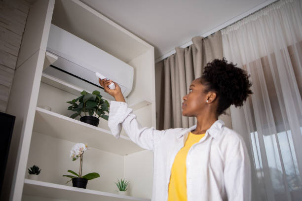istock Young woman turning on air conditioner 1617586827