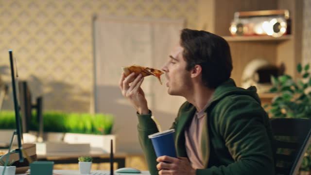 Hungry man taking pizza slice at office closeup. Two startupers enjoying lunch