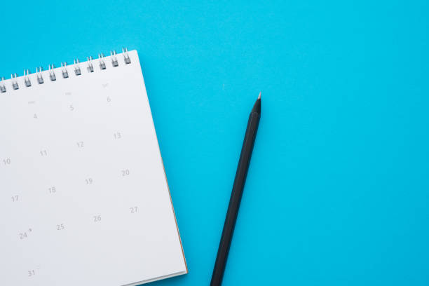 istock Flat lay of white empty clean calendar with pencil on blue background. 1617612887