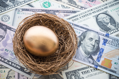 Bright golden egg in nest on US dollar bill cash banknotes background. Rich, wealth, successful from stock dividend in stock market investment. Business, financial, pension, investment and passive income concept.