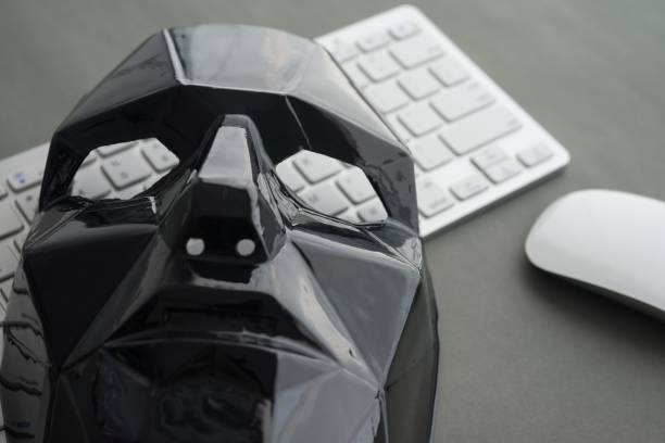 istock Black scary half face mask, keyboard and mouse on gray table background. 1617653036