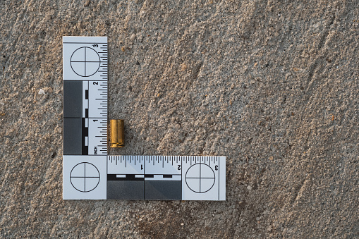 One crime scene evidence ruler on the street after a gun shooting brass bullet shell casing 9mm handgun pistol