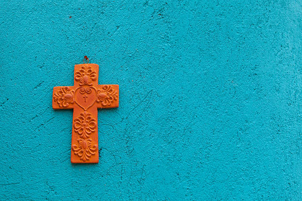 Terracotta cross on a turquoise wall stock photo