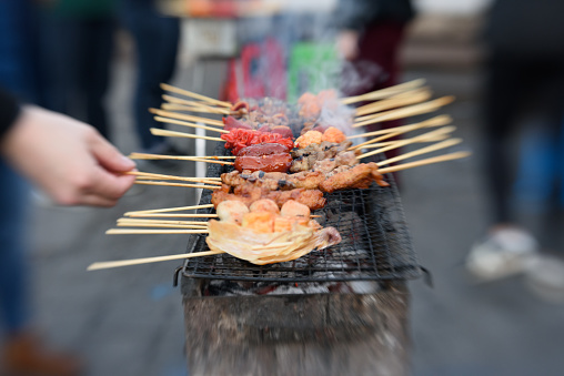 Meat on skewers being cooked over a charcoal grill or ihaw at a Filipino market in Los Angeles