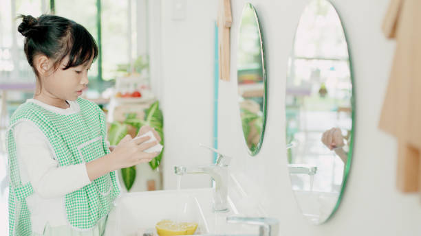 istock Elementary mixed girl washing dishes, practical life skill activity in Montessori education school 1617670575