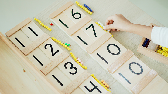 Elementary girl using color bead chain to learn mathematics in Montessori education school and homeschooling