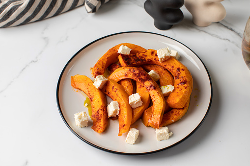 Baked pumpkin slices with spices and cubes of feta cheese. Autumn recipes, pumpkin dishes.