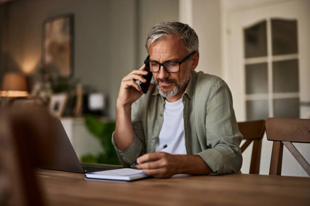 istock Serious senior man talking on a smartphone and taking notes. 1617700753
