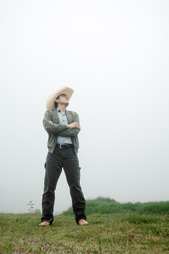 A joyful man donning a Mexican hat and cowboy boots enjoys the misty grasslands, showcasing the spirit of adventure