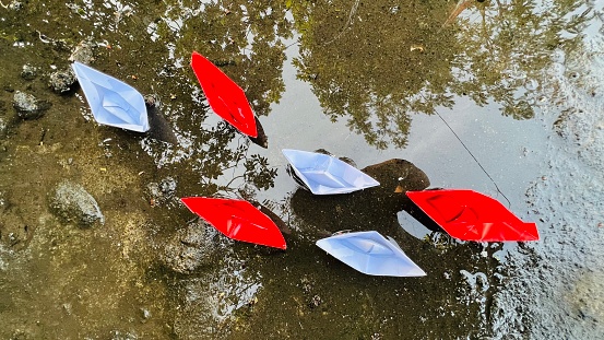 Paper boat Red and white floating on the water.