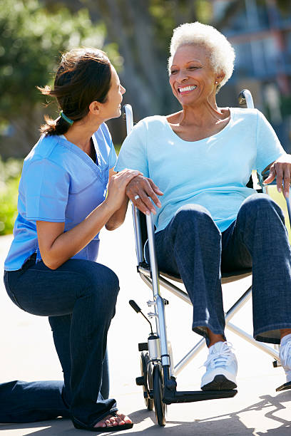 prestador de empurrar mulher idosa na cadeira de rodas - senior adult hospital uniform gray hair imagens e fotografias de stock