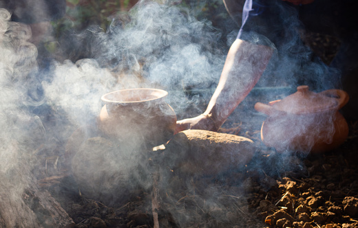 Cooking by using traditional earthware  in dramatic light at camping