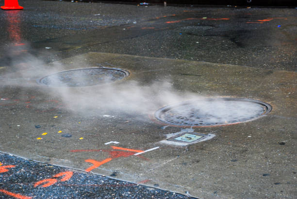 A close-up of a vibrating asphalt compactor (steam roller) rolling over freshly laid asphalt during the resurfacing of a rural highway. The road surface was milled of the old top layer of asphalt and that material is being recycled into aggregate for new asphalt