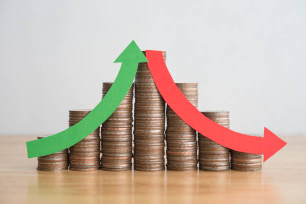 istock Stack coins and arrow red green curve graph chart volatility up and down on wooden table background. 1617841209