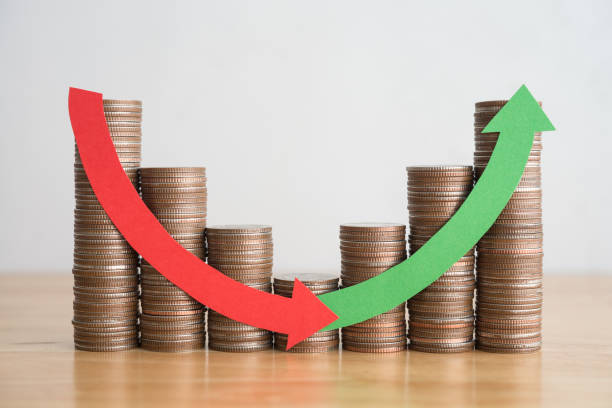 istock Stack coins and arrow red green curve graph chart volatility up and down on wooden table background. 1617841337